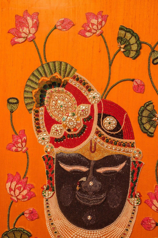 Handcrafted Shrinathji Pichwai artwork in ornate frame, orange silk background, perfect for living room decor by Iragai.