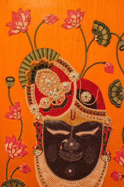 Handcrafted Shrinathji Pichwai artwork in ornate frame, orange silk background, perfect for living room decor by Iragai.