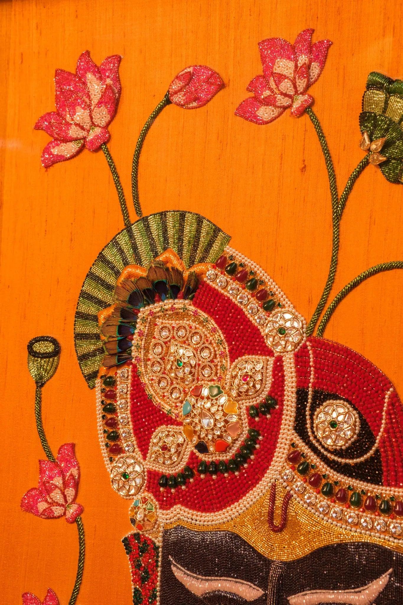 Luxury handmade Shrinathji Pichwai frame adorned with gemstones and beads on vibrant orange fabric by Iragai