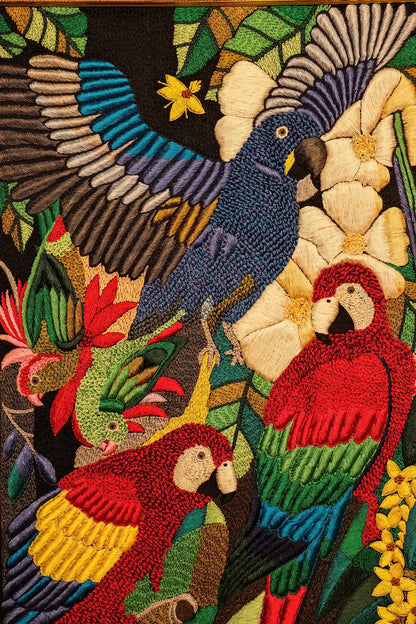 Embroidered design of parrots and flowers with vibrant colors on a dark background