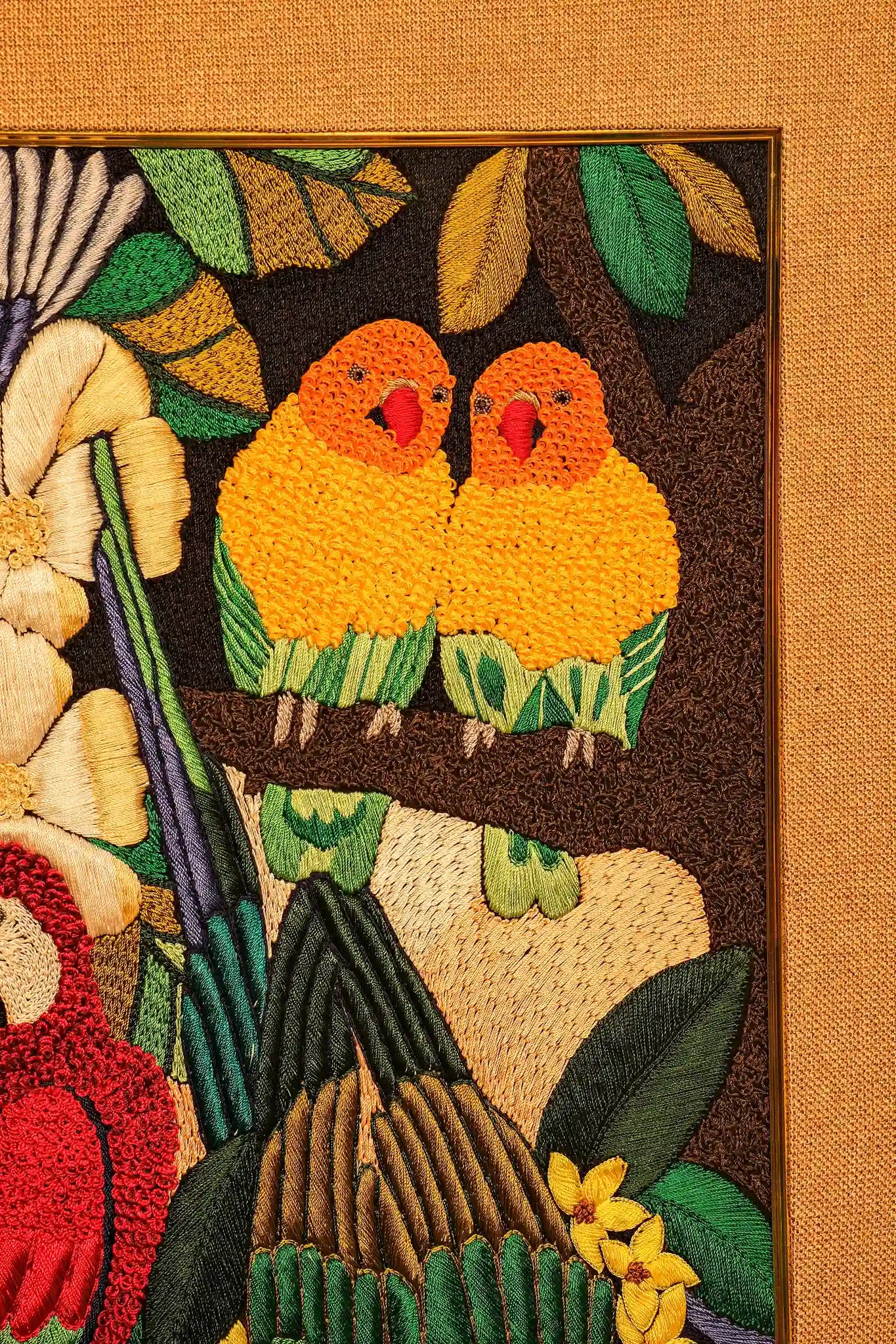 Embroidered panel with two yellow birds on a branch surrounded by leaves and flowers.