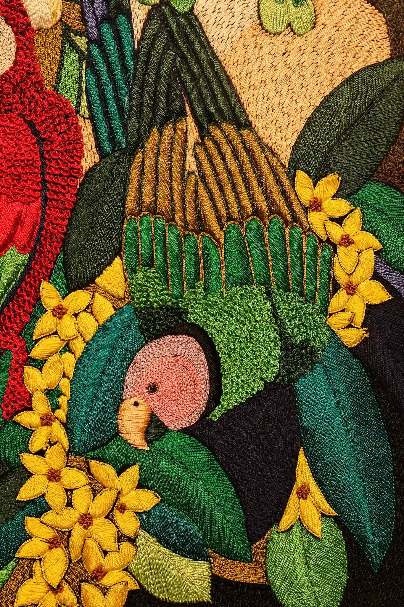 Embroidered design of a toucan surrounded by flowers and leaves