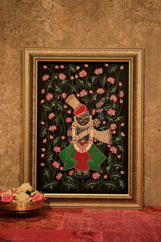 Luxury hand embroidery of a figure with floral motifs in a gold frame on textured wall