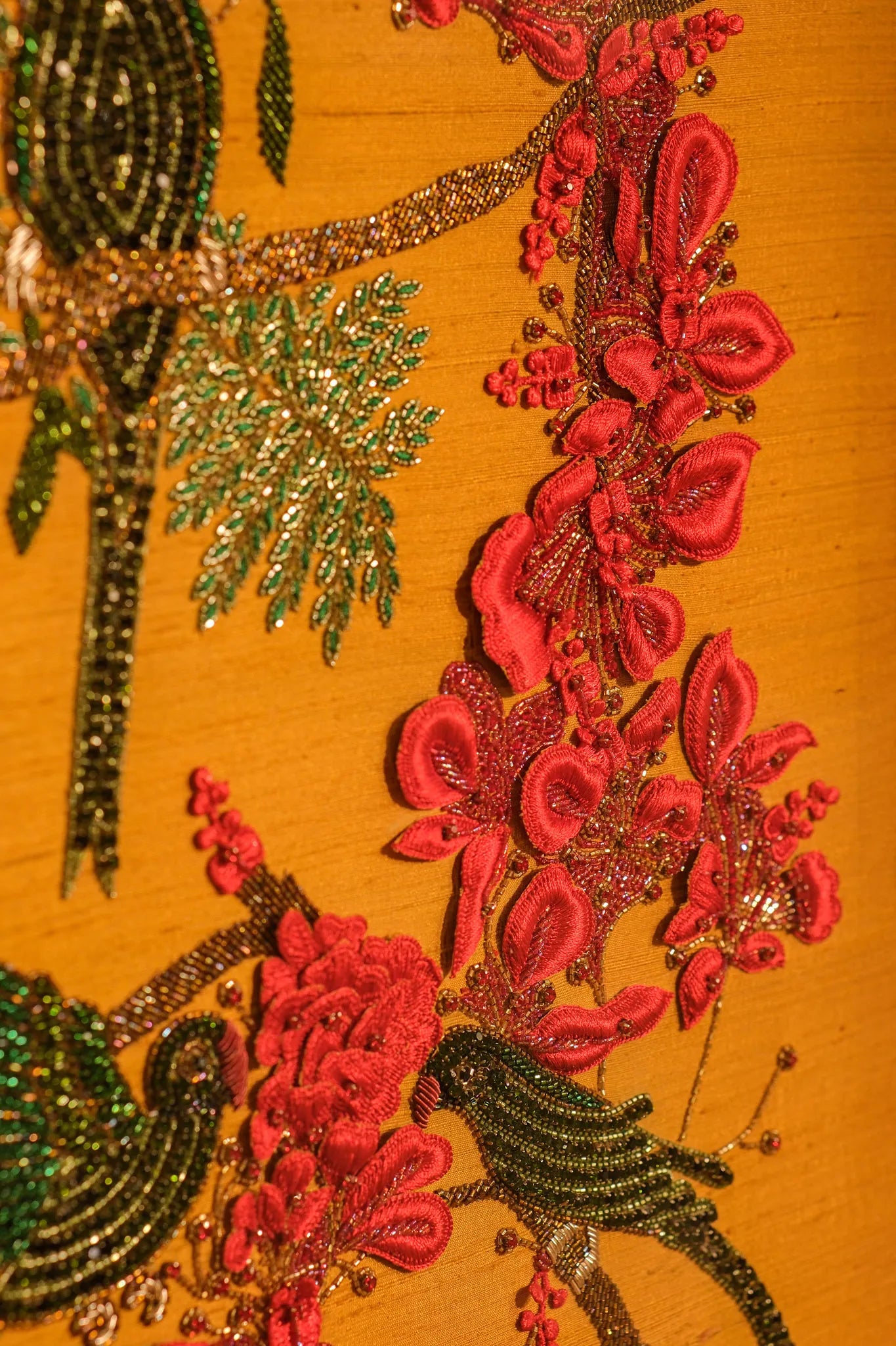 Decorative fabric with red floral patterns and gold embellishments on a yellow background