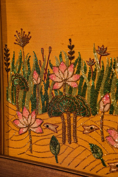 Embroidered design of pink flowers and green leaves on a wooden surface