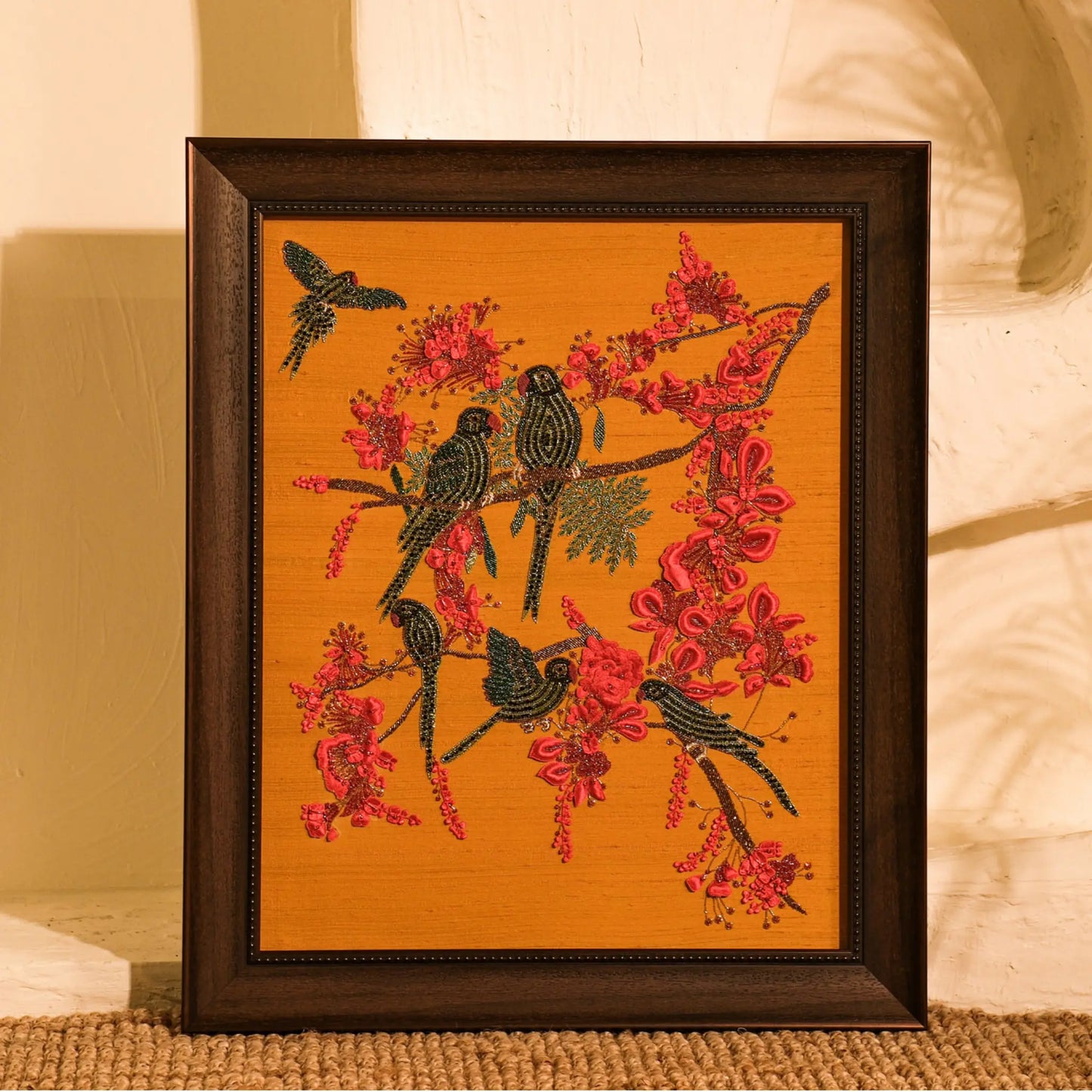 Framed artwork of birds on a branch with red flowers on an orange background